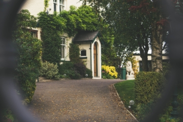 A view of a house through a hole in a fence.