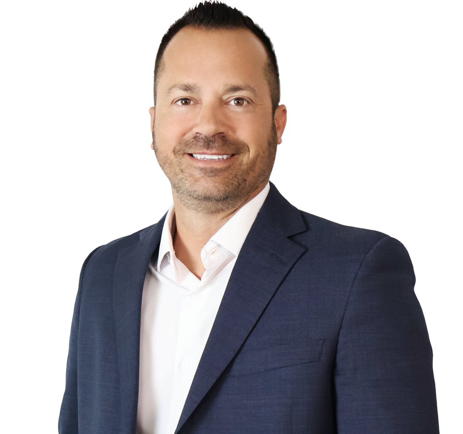 Man wearing a navy blue suit jacket and white shirt, smiling, standing against a plain white background.