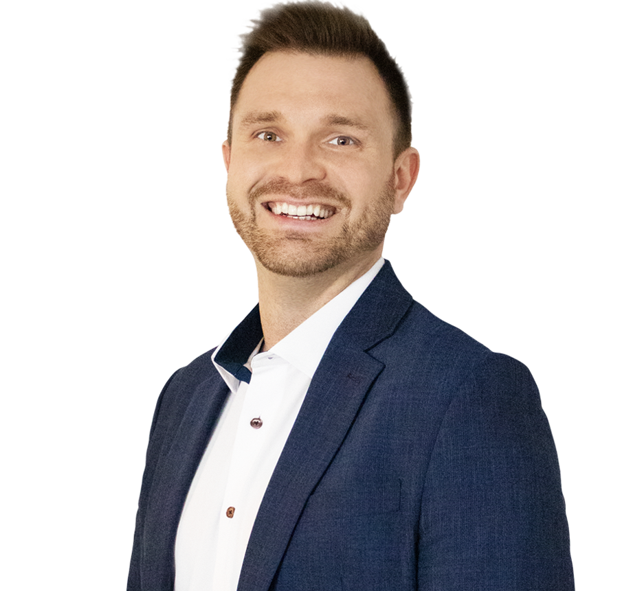 Man in a navy blue blazer and white shirt smiling, standing against a white background.