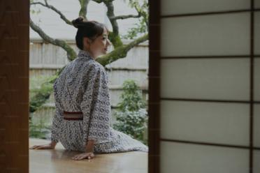 A woman in a kimono sitting in front of a window.