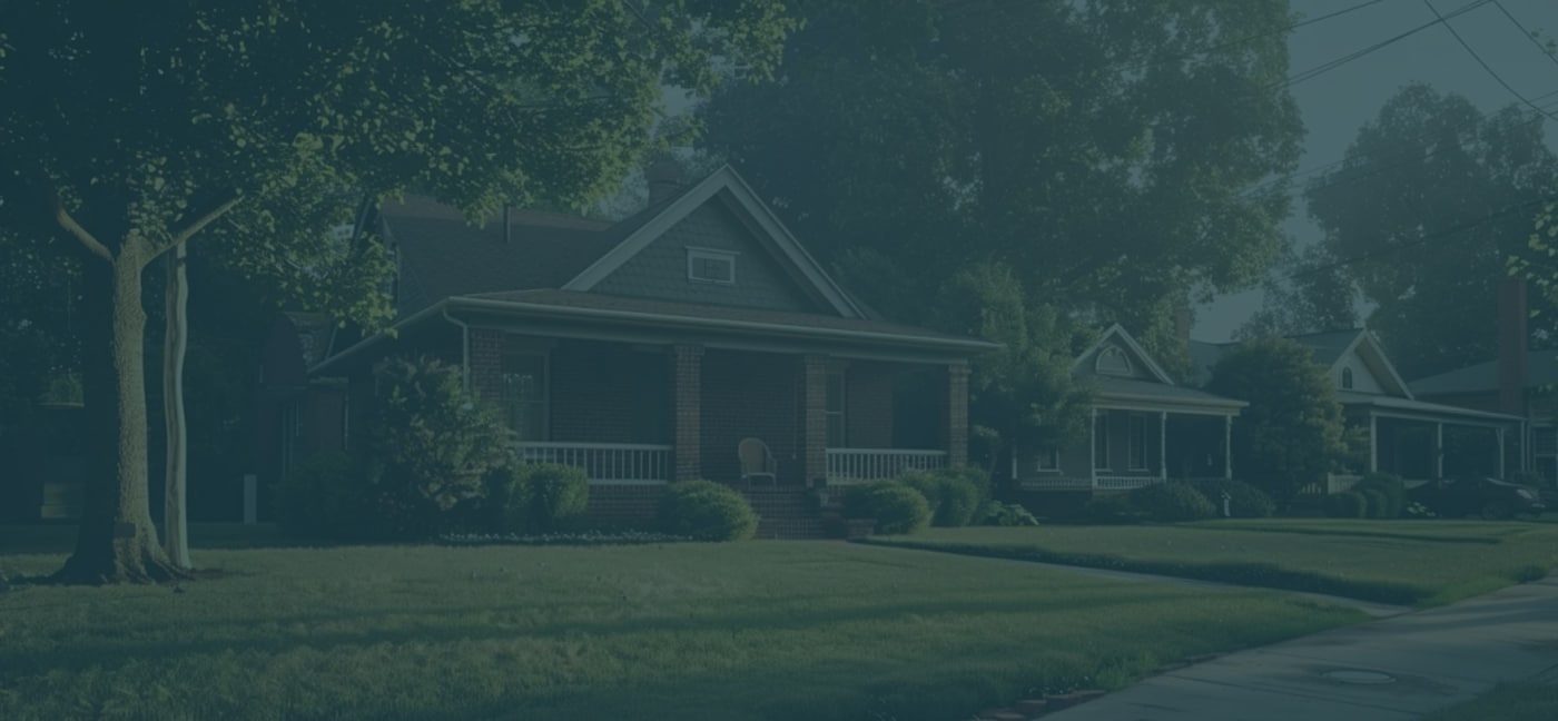 Houses with front porches line a suburban street, surrounded by trees and greenery during daytime.