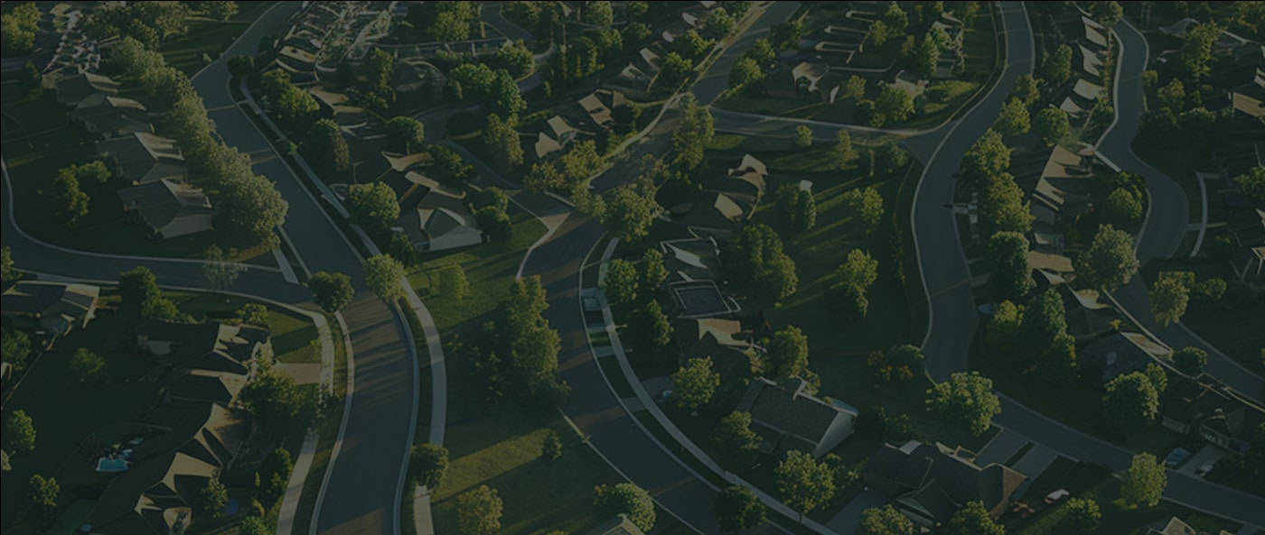 Aerial view of a suburban neighborhood with winding roads, houses, and trees.