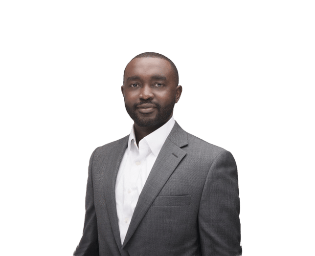 A man in a gray suit and white shirt stands against a plain white background, facing the camera with a neutral expression.