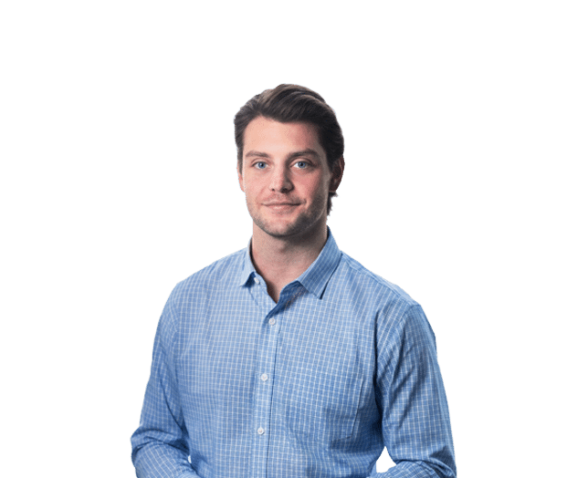 A man with short brown hair wearing a blue plaid button-up shirt stands against a plain white background.